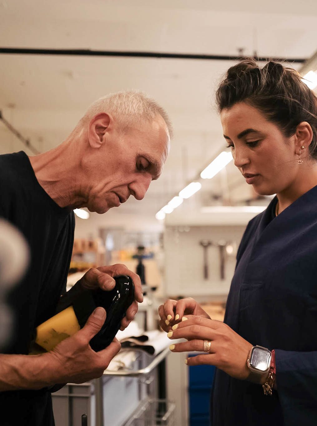 A master maker showing an apprentice a finished shoe