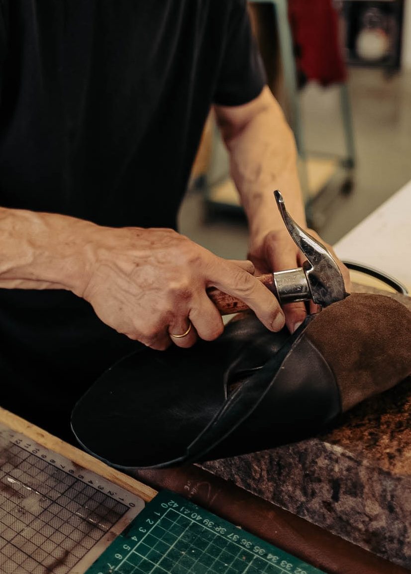 A maker lasting a shoe by hand