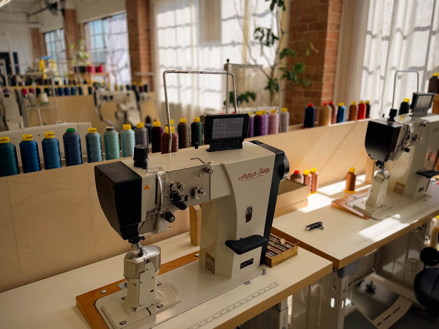 The factory floor: post-bed machines and spools of thread